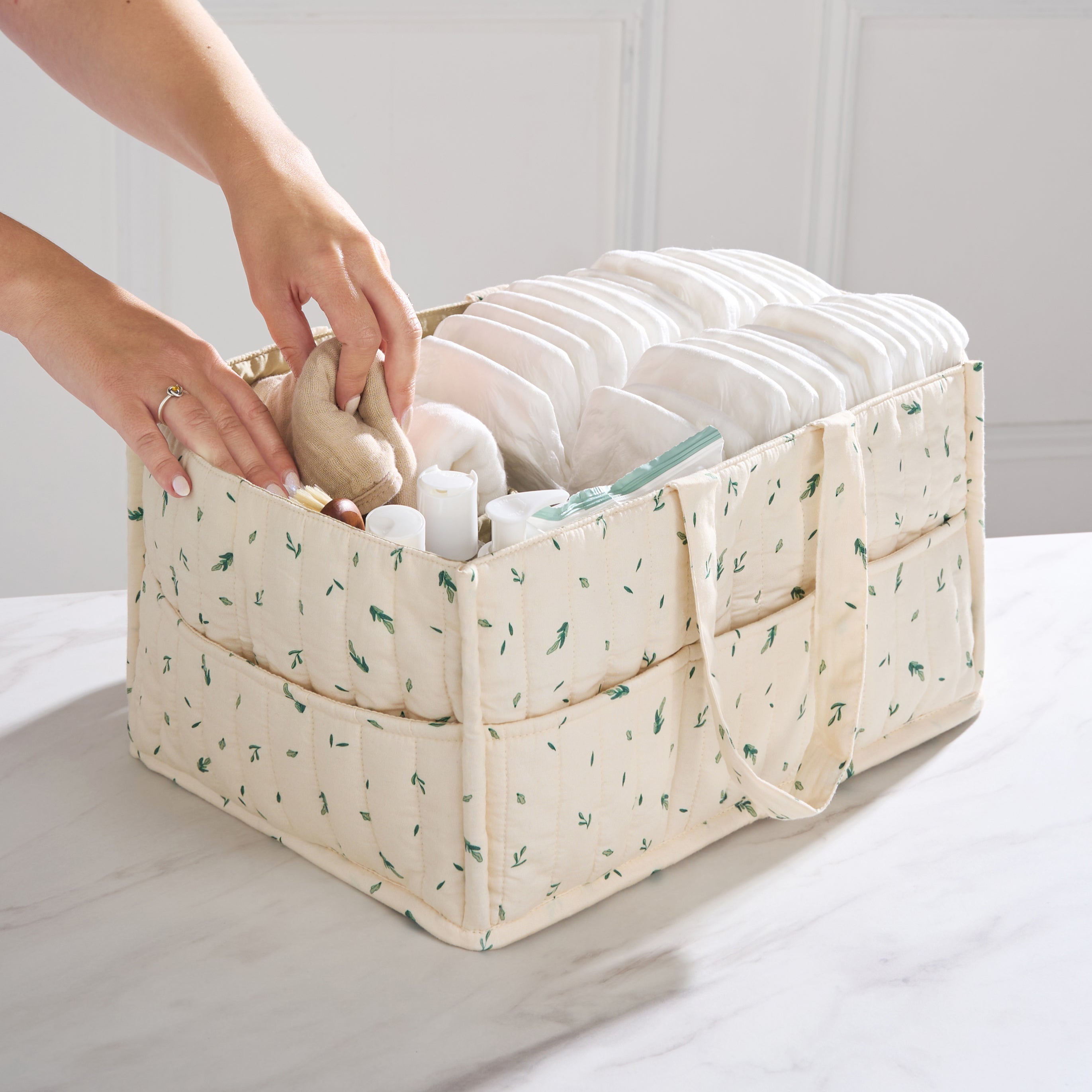 Organic cotton nappy caddy in Linen Leaf print being filled with baby essentials